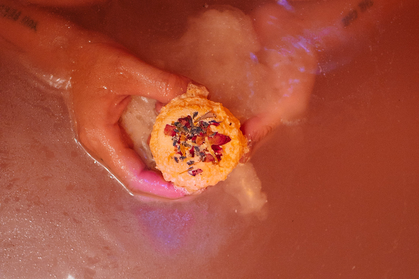 Flower Child Bath Bomb fizzing in water with dried flower petals and citrus aroma.